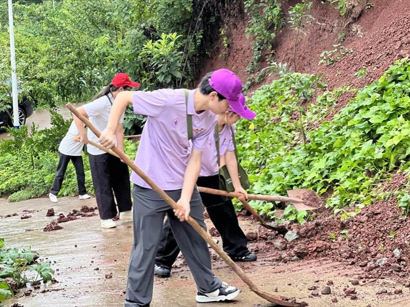 实践团成员帮助老党员清扫路面淤泥