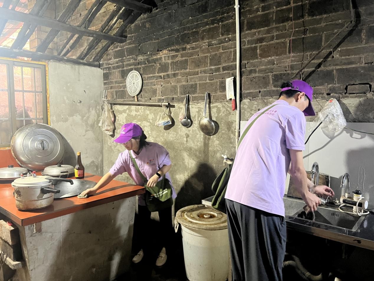 实践团成员帮助老党员清扫路面淤泥